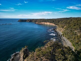 Aerial view of a coastal landscape with cliffs and blue water.