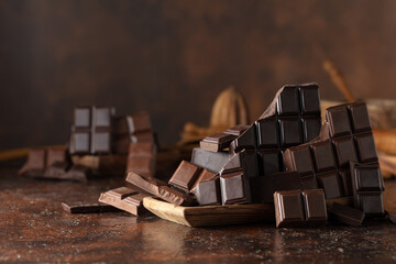 Broken bitter and milk chocolate bars on a brown background.