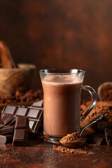 Glass of cocoa drink with ingredients on a brown table.