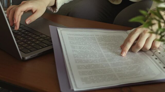 Woman typing on laptop and working remotely from home with documents. Freelancing