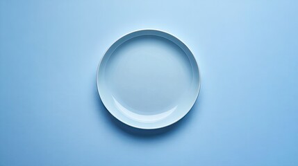 A simple blue ceramic plate neatly arranged on a solid blue table, representing minimalist dining concepts.