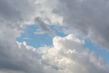 Dynamic sky featuring a mix of fluffy white clouds and darker storm clouds against a bright blue backdrop