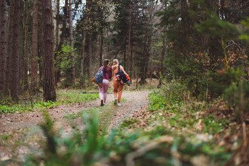 Two young women taking a selfie in a forest, smiling and enjoying their time outdoors having picnic. They are dressed in casual hoodies, surrounded by trees and greenery.