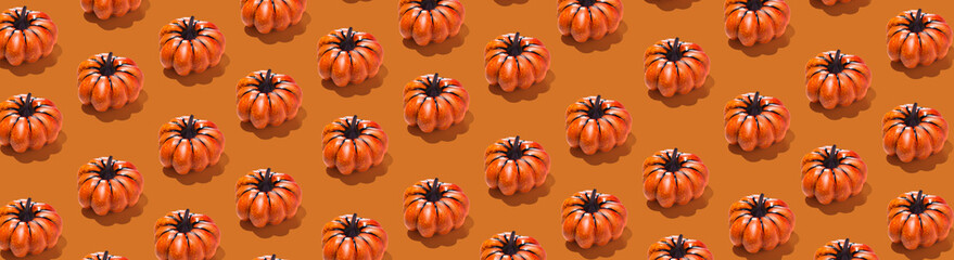 Horizontal banner with pumpkin pattern on orange background. Minimal autumn, Halloween concept