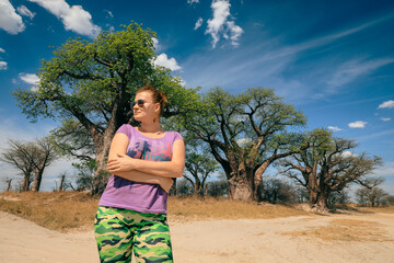 A tourist enjoys the serene landscape of Botswana while exploring the unique baobab trees under a...