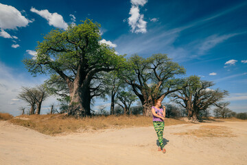 A tourist explores the stunning landscapes of Botswana among iconic baobab trees in the warm...