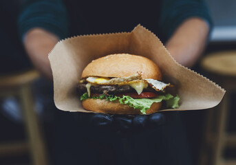 Fresh burger cooked at barbecue outdoors in craft paper. Cookout american bbq food. Big hamburger...