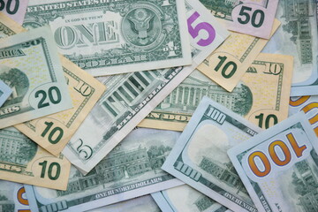 Big amount of US dollar bills in different nominations on table. Many dollar banknotes under natural light