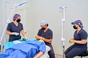 Medical team performing hair transplant surgery on patient in clinical setting