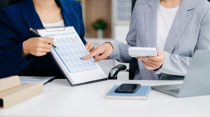 Two business workers talking on the smartphone and using laptop at office