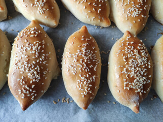Delicious traditional oriental baked pies with filling, sprinkled with sesame seeds and black cumin