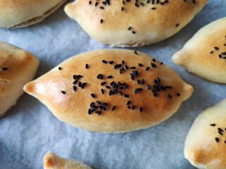 Delicious traditional oriental baked pies with filling, sprinkled with sesame seeds and black cumin