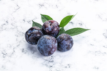Raw purple plums heap with leaves