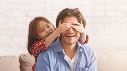 Little Girl Covering Her Father Eyes With Palms, excited dad is smiling, panorama with copy space