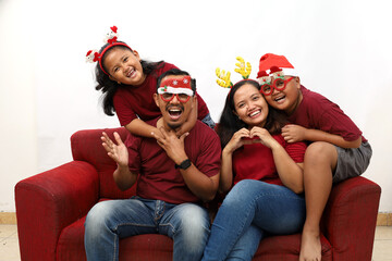 Asian family celebrating Christmas and New Year while sitting on red sofa. Isolated on white background