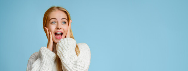 Shocking advertisement. Shocked winter girl with open mouth and hands on face looking at empty space, panorama
