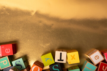 A scattering of colorful alphabet blocks spell out tax on a gold background