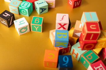 A colorful jumble of wooden alphabet blocks on a golden surface Let the learning begin
