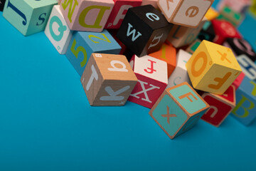 A colorful jumble of alphabet blocks scattered on a blue background Learning is fun