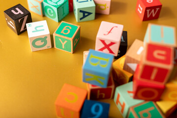 Colorful alphabet blocks scattered on a golden surface Learning is fun