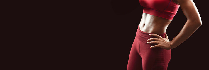 Obraz premium Athletic body of african female fitness model over black background, cropped, free space