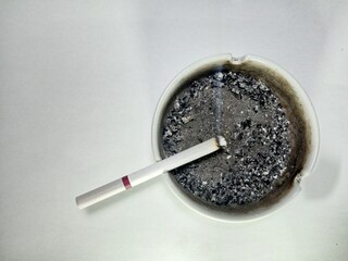 a close-up of a cigarette resting in a full ashtray, surrounded by burnt ash. the image conveys the idea of smoking, health concerns, or addiction. ideal for anti-smoking campaigns.