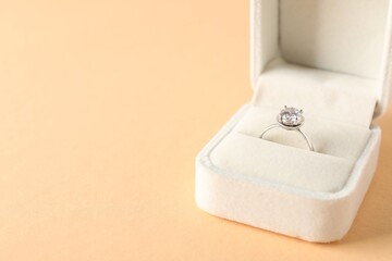 Beautiful ring with gemstone in box on beige background, closeup. Space for text