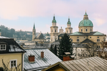 Naklejka premium Winter views of Salzburg showcasing historic architecture and snow-dusted rooftops against a pastel sky