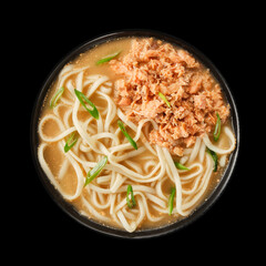 Delicious bowl of noodles topped with shredded chicken and green onions, served on a black background