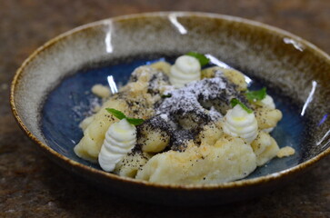 blue plate with traditional Czech sweet food, potato gnocchi with poppy seeds and cottage cheese, background of served food, fruit decorated