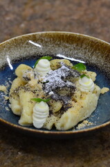 blue plate with traditional Czech sweet food, potato gnocchi with poppy seeds and cottage cheese, background of served food