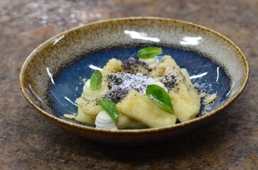 blue plate with traditional Czech sweet food, potato gnocchi with poppy seeds and cottage cheese, background of served food, fruit decorated