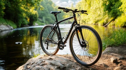 Fototapeta premium A mountain bike resting on a rock by a serene river surrounded by lush greenery.