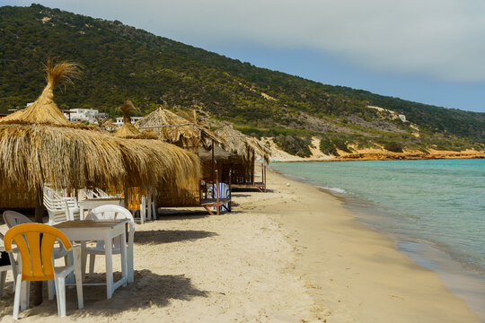 Beach tables and Cabanas on beach and mountain in background
