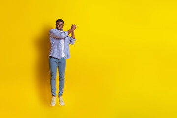 Full length photo of cheerful positive guy dressed checkered shirt jumping high flying parasol emtpy space isolated yellow color background