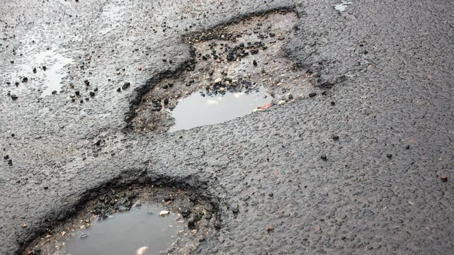 A hole in the asphalt. Damaged asphalt road, a hole in the asphalt surface. Puddle in the asphalt hole, repair, restoration of pavement, animation