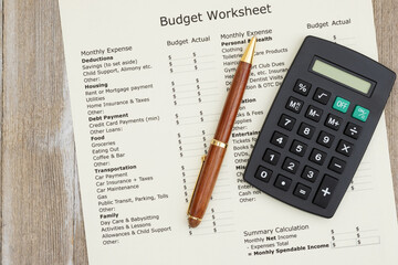 Monthly personal budget with a pen and calculator on wood desk