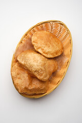 Crispy and golden puris stacked in a woven basket ready to be served at a festive gathering