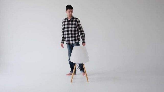 Portrait of a positive, cheerful Caucasian man sitting on chair and looking at camera on white background. Positive people and emotions concept.