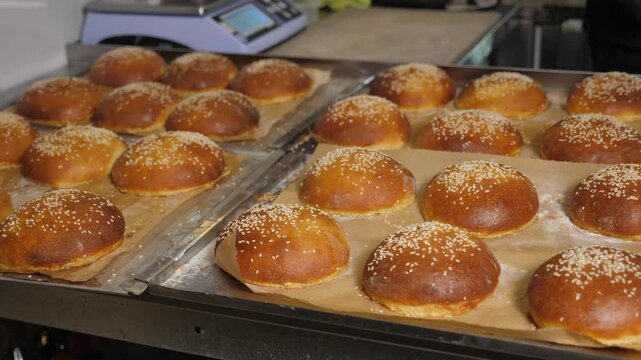 Close-up of freshly baked burger buns with sesame seeds in the restaurant kitchen. Fresh burger buns with a crispy crust. 
