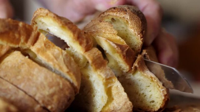 Close-up of hands slicing Matera bread with a knife, highlighting the texture and quality of the traditional Italian loaf.