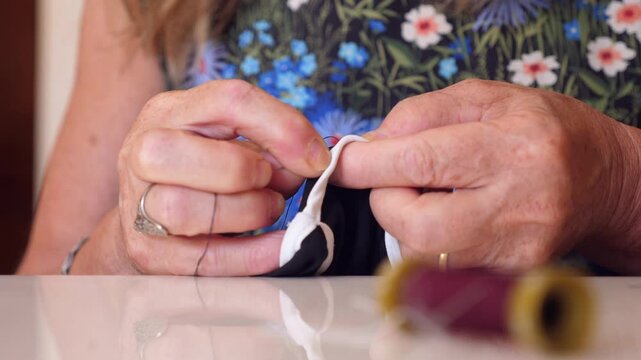 Hands mending a torn bra, detailed and delicate repair work. The careful stitching restores the garment to its original condition