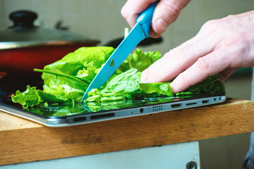 Cutting salad on the surface of an electronic tablet.