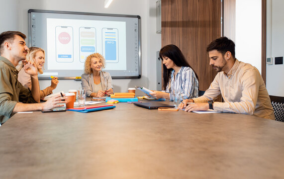 Group of business people sitting in a meeting room discussing a design for a smartphone application.