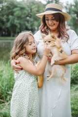 A woman and a little girl holding a fawncolored dog