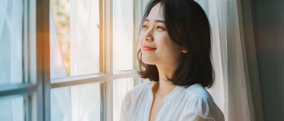 A content woman enjoys the golden hour by the window, eyes closed and wearing a soft smile, embraced by the gentle morning light.