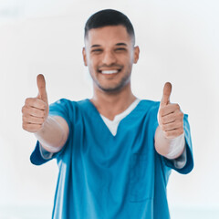 Portrait, surgeon or happy man with thumbs up for success, welcome or thank you in hospital. India, support or proud medical male nurse with hand gesture for approval, agreement or yes for healthcare