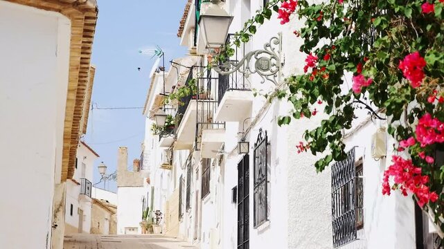 Beautiful narrow street with white facade houses in coastal historical town Altea, Spain