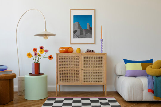 Fototapeta Minimalist living space with vibrant accents, including a rattan cabinet, geometric artwork, and colorful flowers in a modern vase.