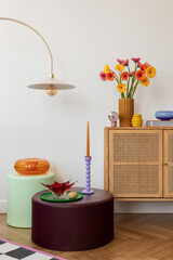 Mid-century modern sideboard with a floral vase, colorful candles, and a vibrant wall art print. Minimalist yet playful interior decor.